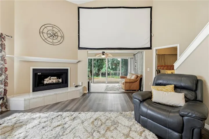 Vaulted living room with a fireplace featuring a tiled hearth and mantel