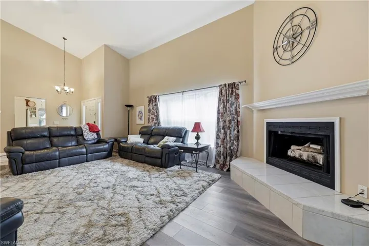 Spacious living area featuring vaulted ceilings, a built-in fireplace with a tiled hearth and white mantle, and wood-finish flooring