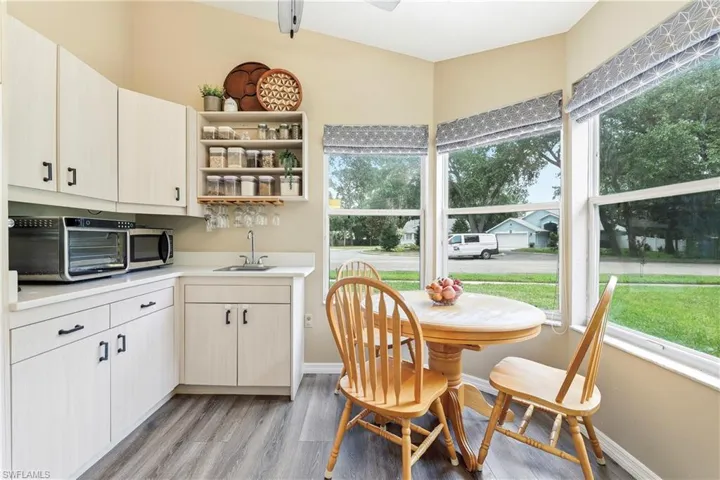 Kitchenette featuring light-toned cabinetry with black hardware, a stainless steel sink, and light countertops