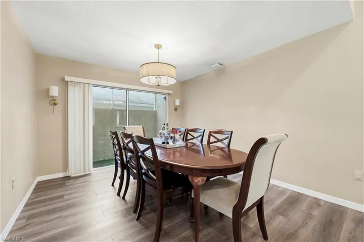 Dining area featuring wood-finish flooring, a contemporary drum pendant light, and two wall sconces