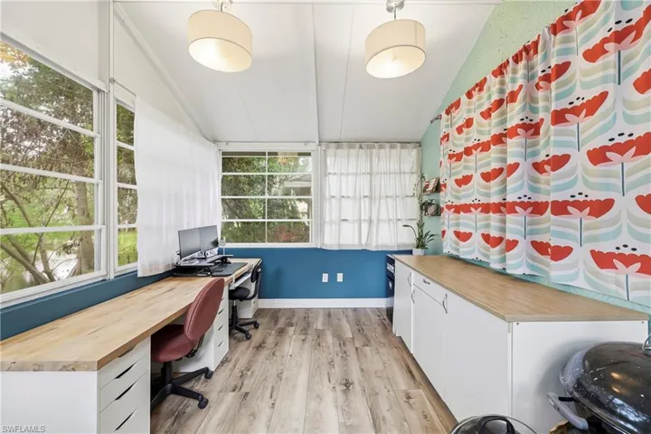 Sunroom featuring wood-finish flooring, multiple windows, a sloped ceiling, and built-in cabinetry with wood-finish countertops