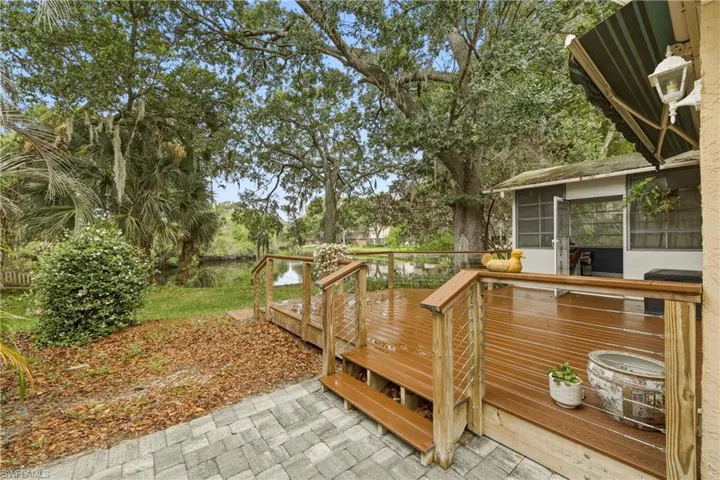 Expansive wood-finish deck with cable railing overlooking a water feature
