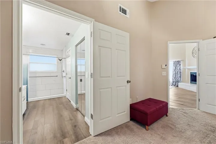 Bathroom entry with wood-finish flooring, white subway tile shower surround, and a clear window
