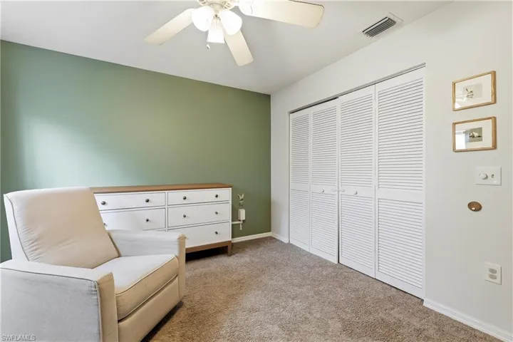 Bedroom featuring louvered bi-fold closet doors, wall-to-wall carpeting, a ceiling fan, and painted walls