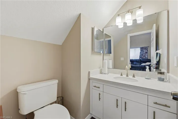 Bathroom vanity featuring a light-toned countertop, integrated sink, and white cabinetry with brushed nickel hardware