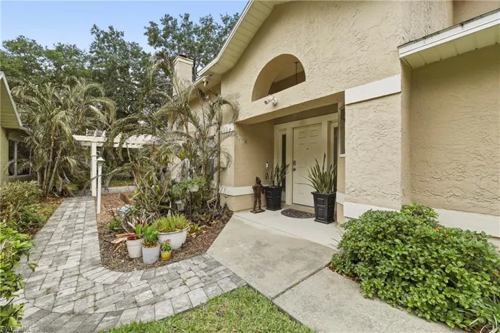 Stucco exterior with an arched entryway and a solid panel front door