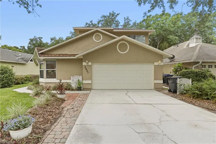 Stucco exterior featuring a two-car garage, bay window, and a brick paver walkway
