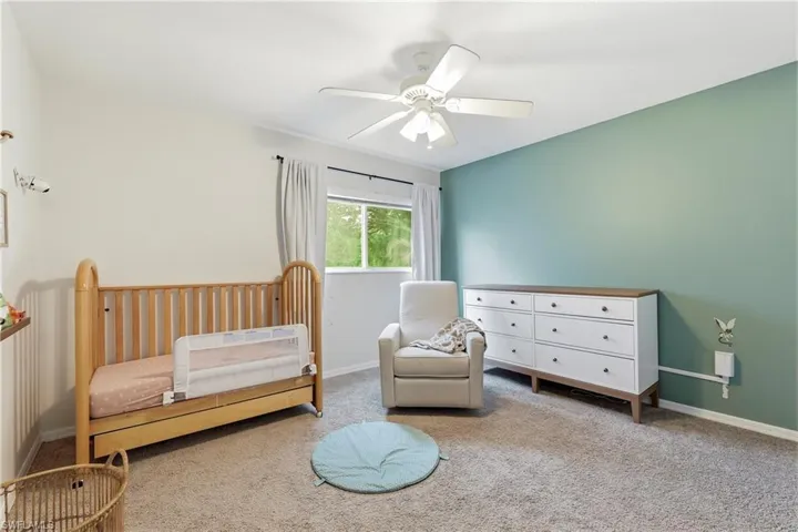 Carpeted room featuring a ceiling fan, a window with curtains, and a two-toned accent wall