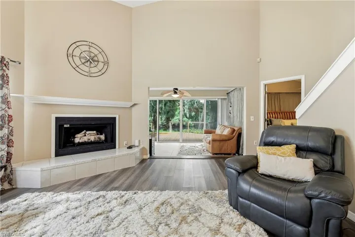 Living area featuring vaulted ceilings, wood-finish flooring, and a fireplace with a tiled hearth and mantel