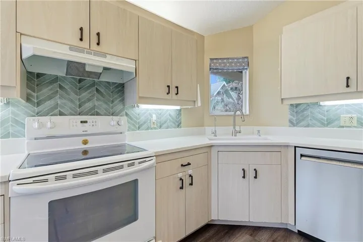 Kitchen featuring light wood-finish cabinetry, white countertops, and a full suite of appliances including a white range and stainless steel dishwasher