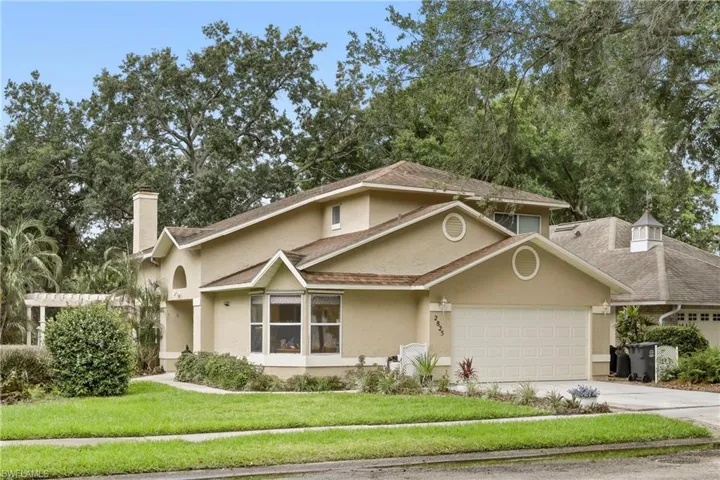 Stucco-clad residence featuring multiple gables and a two-car garage