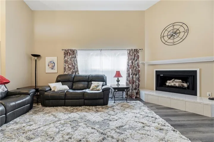 Vaulted ceiling living area featuring a fireplace with a white mantel and tile hearth