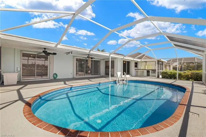 View of pool featuring a patio area, glass enclosure, and ceiling fan