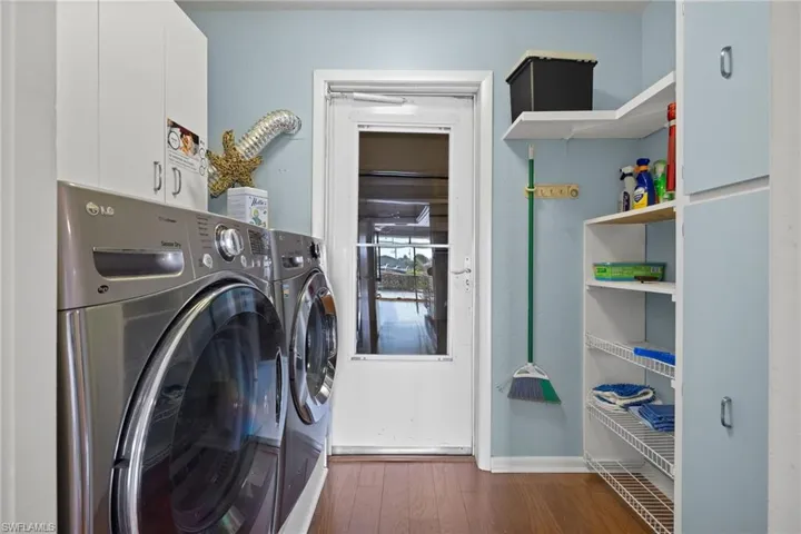 Laundry room featuring washer and clothes dryer, dark hardwood / wood-style floors, and cabinets