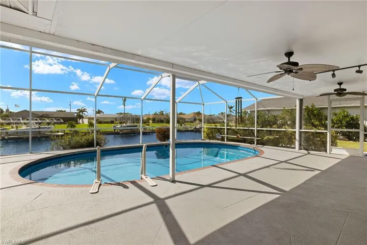 View of pool with a patio, a lanai, a water view, and ceiling fan