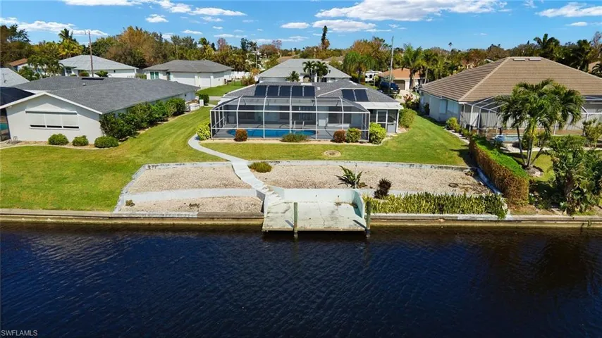 Back of property with a water view, a lanai, and a yard