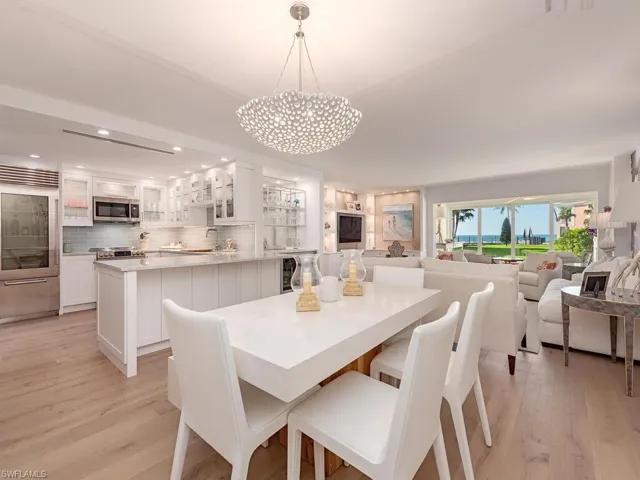 Dining area featuring light wood-style floors, recessed lighting, beverage cooler, and a chandelier