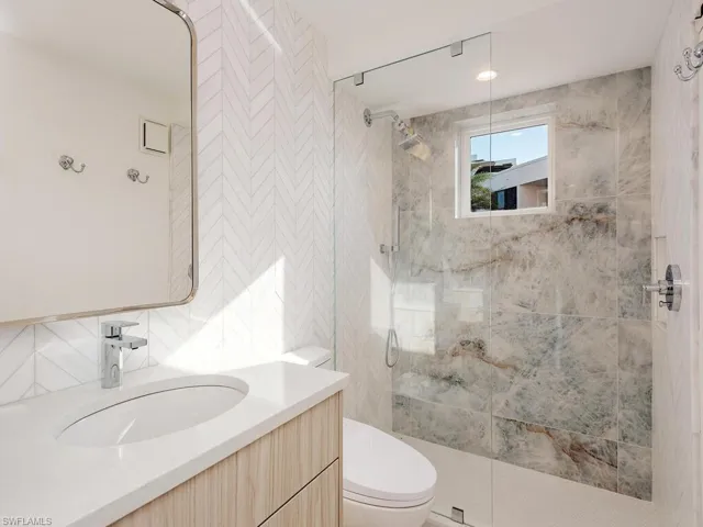 Full bathroom with vanity, a stall shower, and tile walls