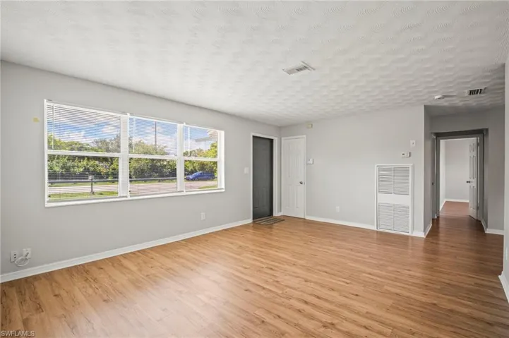 Empty room featuring light wood-style floors, a textured ceiling, and a heating unit