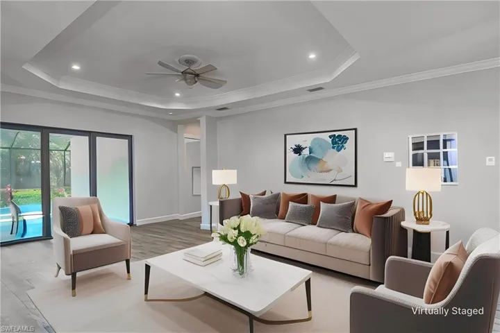 virtually stage - Living room featuring light wood-type _ flooring, crown molding, ceiling fan, and a raised ceiling
