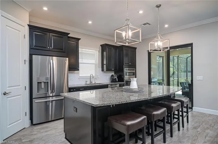 Large pantry, stainless appliances, island with storage on both sides, upgrades galore - impact sliders to lanai and outdoor kitchen