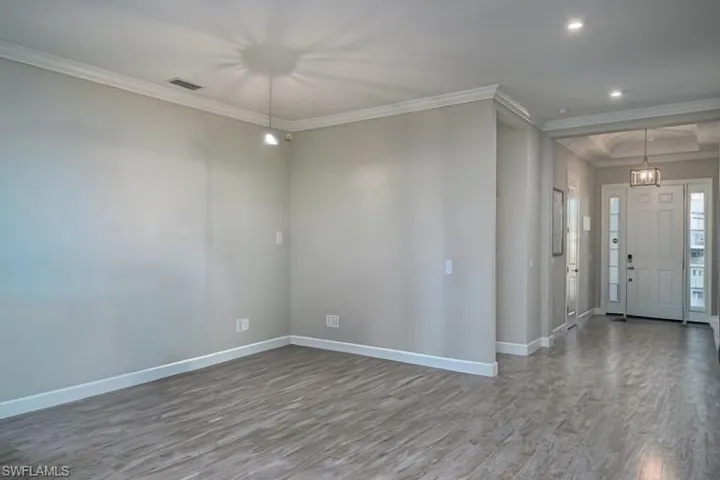 Front room Empty room with ceiling fan, dark wood-type flooring, and plenty of natural light