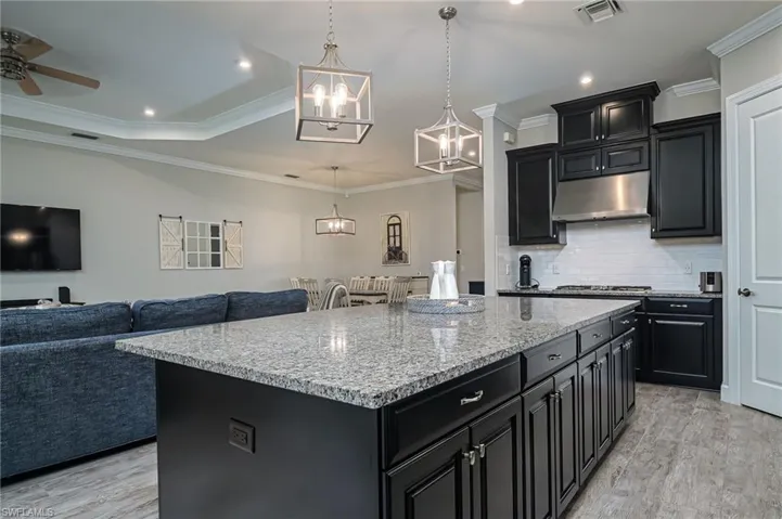 Large island with storage and seating, stainless gas grill, stainless appliances, and pantry