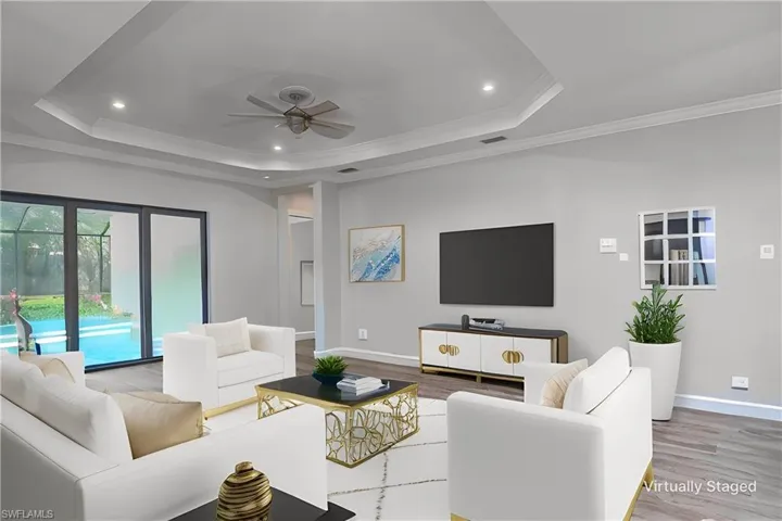 Another virtually staged idea- Living room with light hardwood / wood-style flooring, ornamental molding, ceiling fan, and a raised ceiling