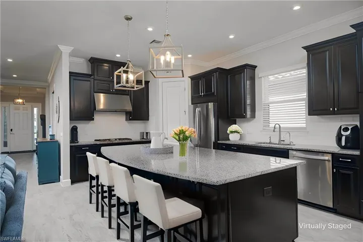 Kitchen featuring hanging light fixtures, a center island, ornamental molding, stainless steel appliances, and sink