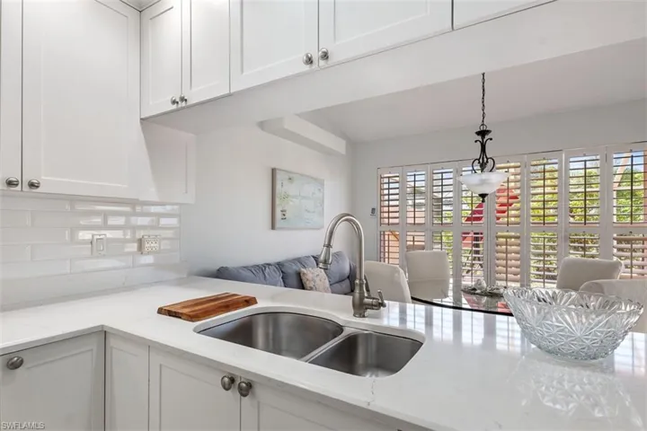 Kitchen with white cabinets, tasteful backsplash, decorative light fixtures, light stone countertops, and open floor plan