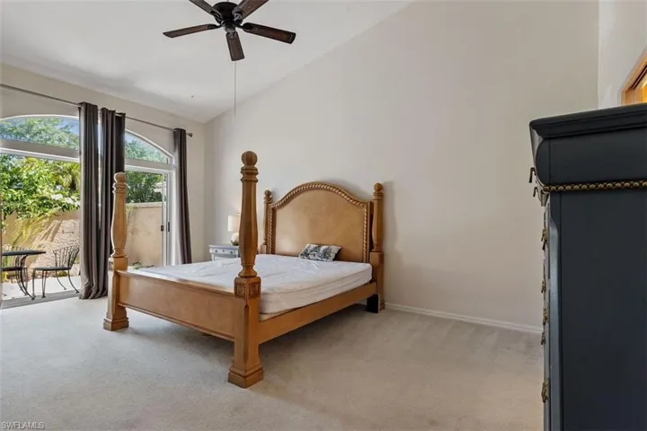 Bedroom with lofted ceiling, light carpet, and a ceiling fan