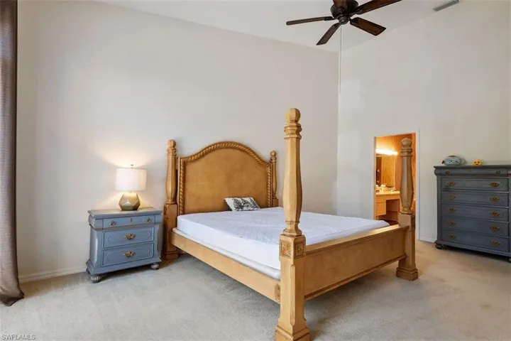 Bedroom with light colored carpet, connected bathroom, and a ceiling fan