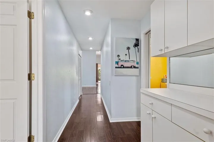 Corridor with dark wood-style flooring and recessed lighting