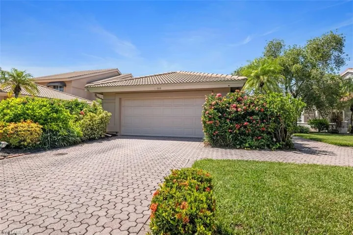 View of front of home featuring decorative driveway, stucco siding, a front lawn, and a tiled roof