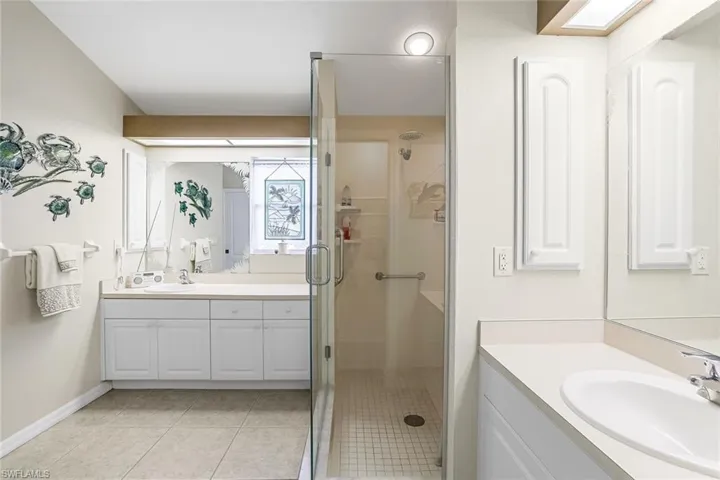 Bathroom featuring tile flooring, an enclosed shower, and dual vanities