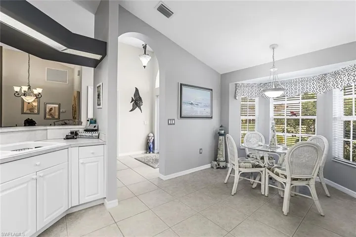 Tiled additional dining area within the kitchen area, featuring a notable chandelier and high vaulted ceiling, large bay window.