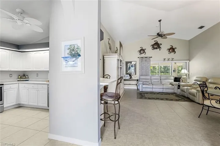 Kitchen with ceiling fan, white cabinetry, and light tile floors