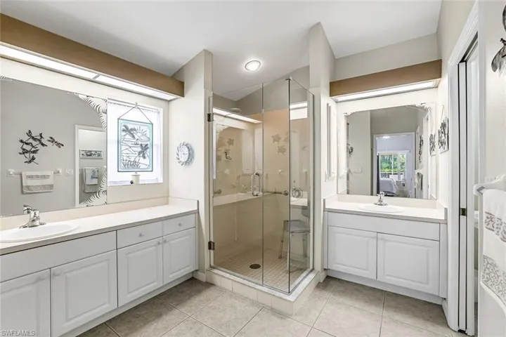 Bathroom with tile floors, an enclosed shower, and dual vanities