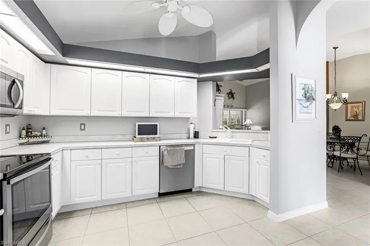 Kitchen featuring decorative light fixtures, white cabinets, ceiling fan, appliances with stainless steel finishes, and light tile floors