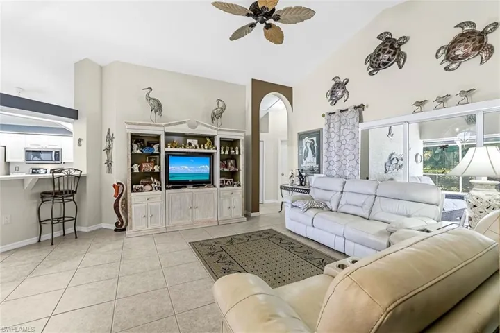 Tiled living room featuring high vaulted ceiling and ceiling fan