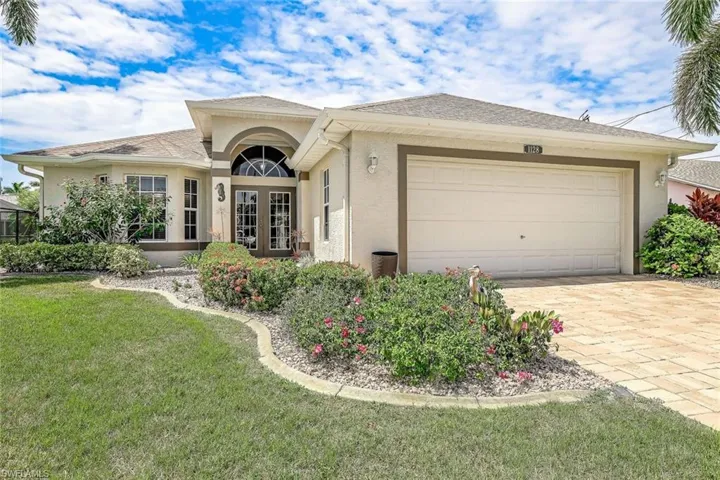 View of front facade featuring a garage and a front lawn