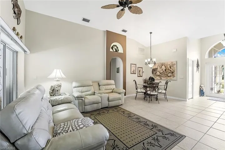Living room featuring high vaulted ceiling, light tile floors, and ceiling fan