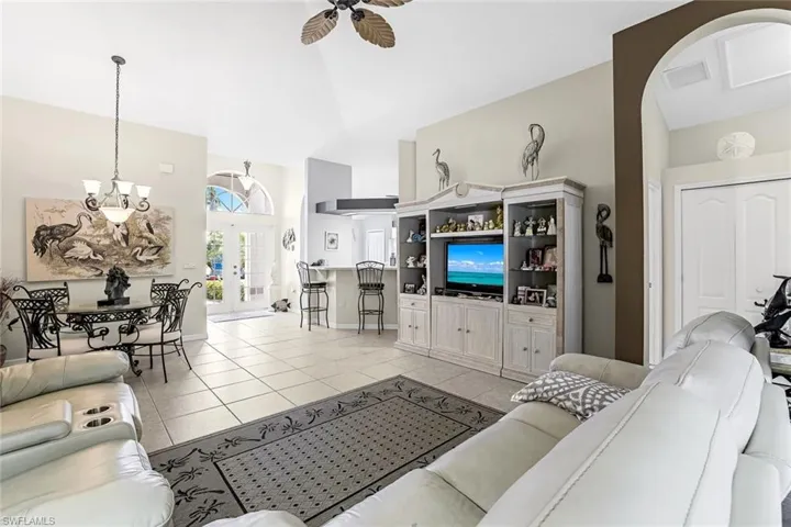 Tiled living room with a high ceiling, ceiling fan, and french doors