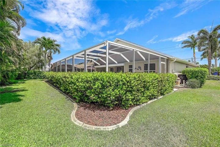 View of side of home featuring a lanai and a lawn