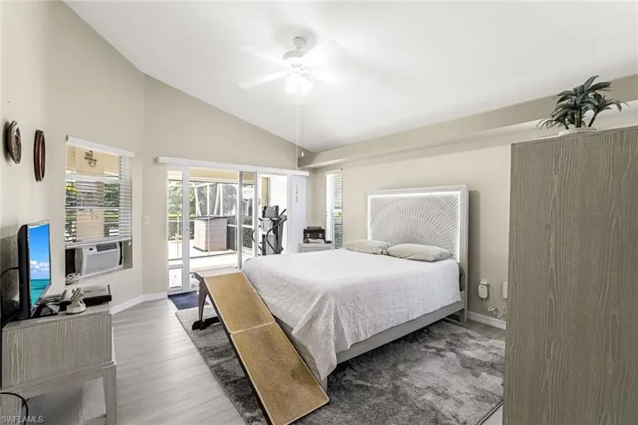Bedroom with vaulted ceiling, LVP flooring, ceiling fan, and access to exterior