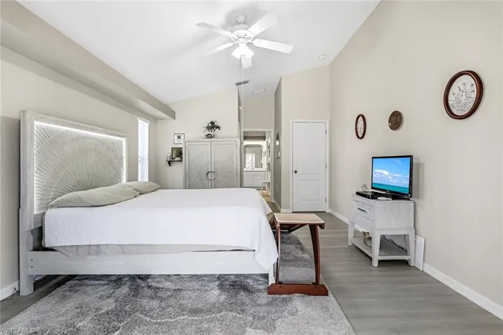 Bedroom with vaulted ceiling, LVP floors, ensuite bathroom, and ceiling fan