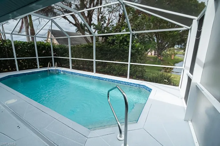View of pool with a water view, a patio area, glass enclosure, and ceiling fan
