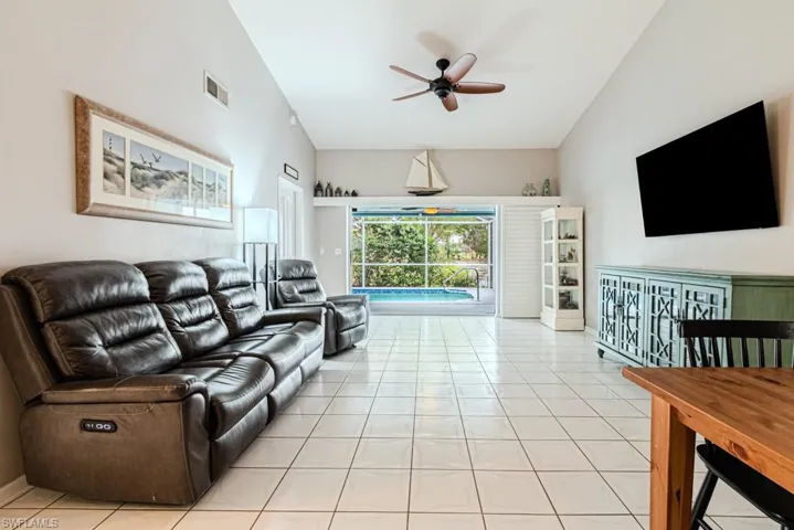 Tiled living room featuring high vaulted ceiling and ceiling fan