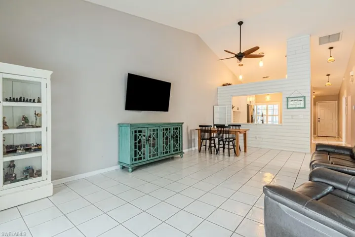 Dining room featuring a healthy amount of sunlight, light tile patterned flooring, high vaulted ceiling, and ceiling fan