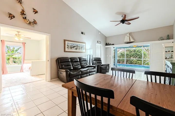 Living room with ceiling fan, high vaulted ceiling, and light tile patterned floors